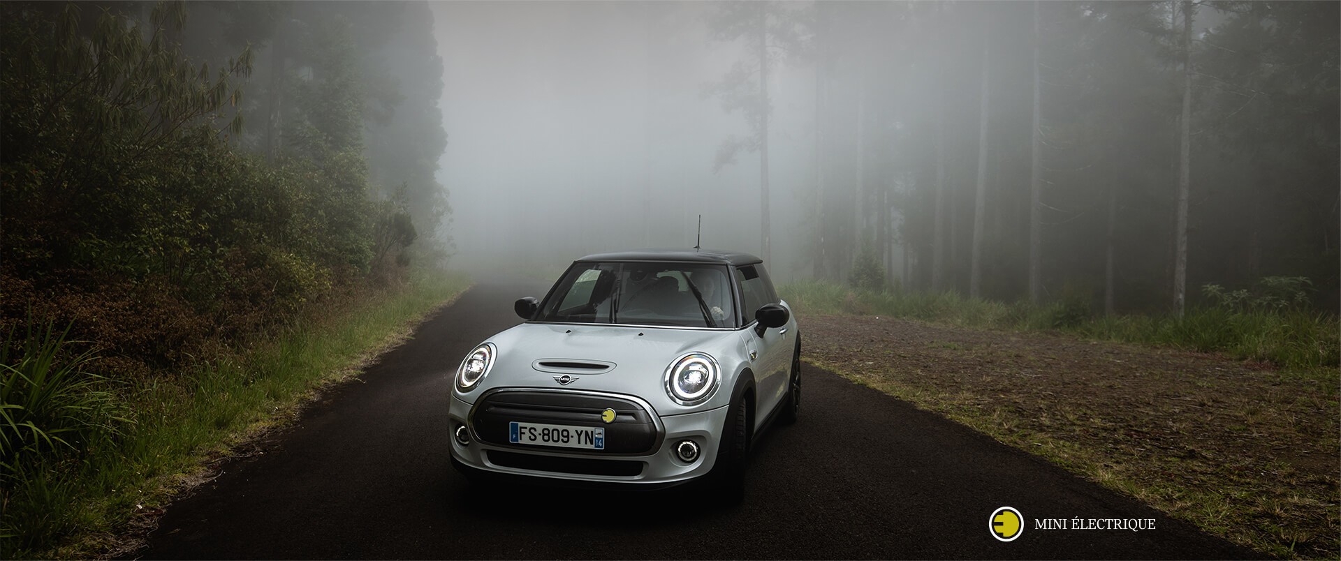 MINI Electric parked on foggy road.